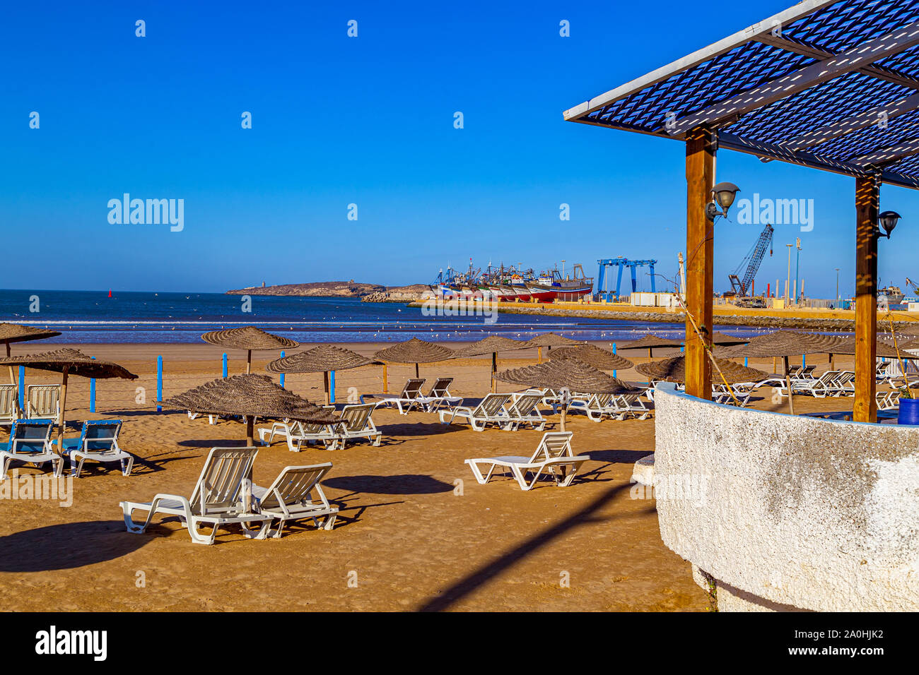 La lumière du matin sur la plage déserte avec mouettes et port avec bateaux de pêche colorés à Essaouira, Maroc.L'Afrique du Nord. Banque D'Images