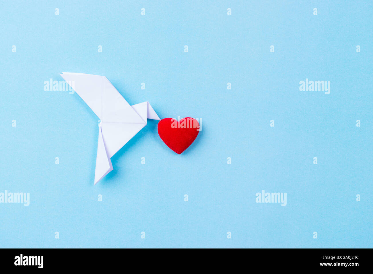 Oiseau blanc en papier portant cœur rouge. Journée internationale de la paix. Banque D'Images