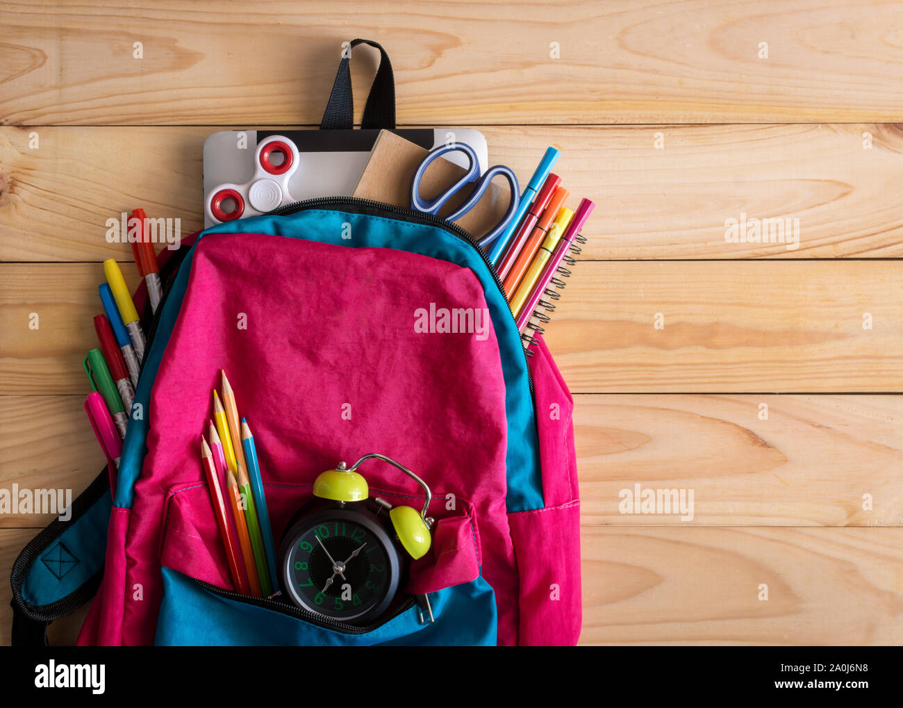 Sac à dos pour l'école avec des fournitures scolaires et de l'horloge sur  fond de table en bois. Concept Retour à l'école Photo Stock - Alamy