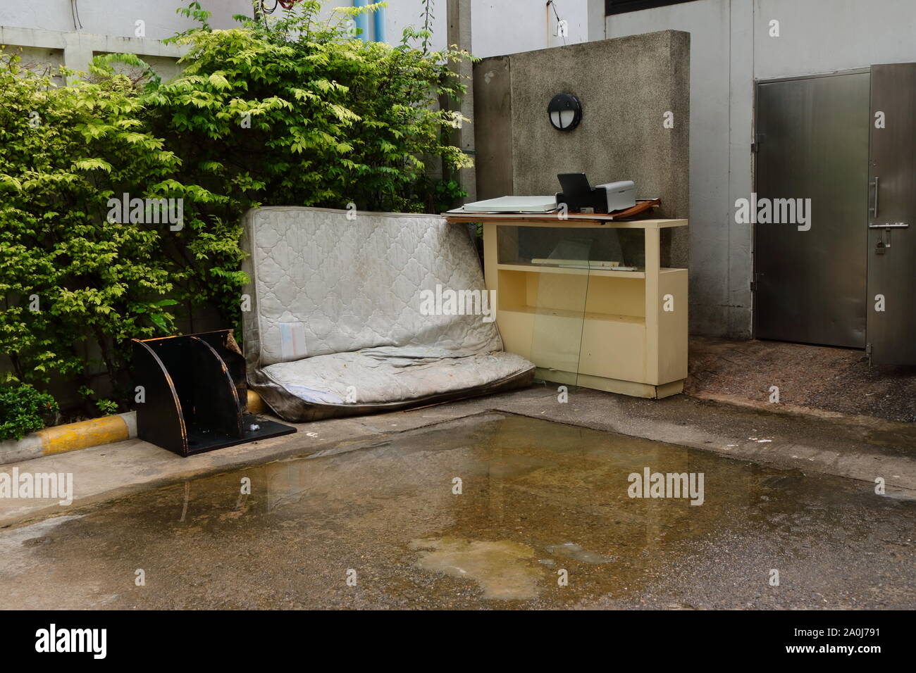 Gros plan du matelas blanc mis au rebut et du cabinet jetés à l'angle en face de décharge Banque D'Images