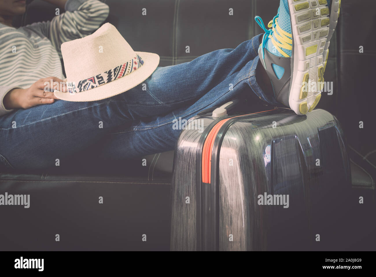Voyageuses met la sienne sur les jambes de voyage lors de l'attente à l'aéroport. Concept de voyage. Banque D'Images