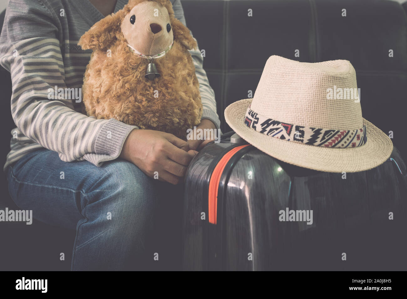 Voyageuses avec le sien les moutons poupée, sac de voyage et chapeau de paille, en attendant à l'aéroport. Concept de voyage. Banque D'Images