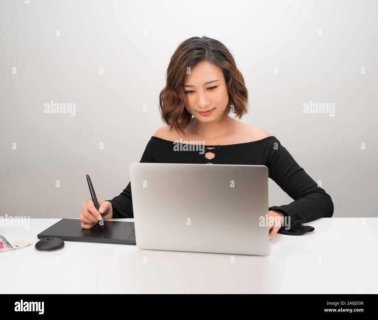 Jeune femme d'origine asiatique concepteur à l'aide de tablette graphique tout en travaillant avec l'ordinateur Banque D'Images