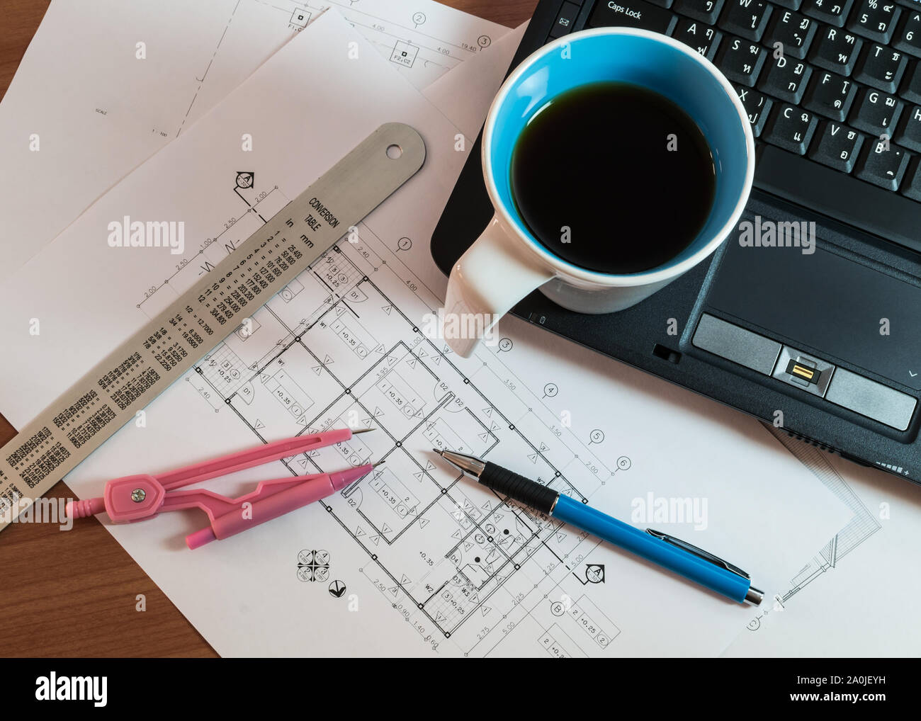 Tasse de café sur l'ordinateur portable avec les plans de construction, matériel de dessin et de plumes Banque D'Images