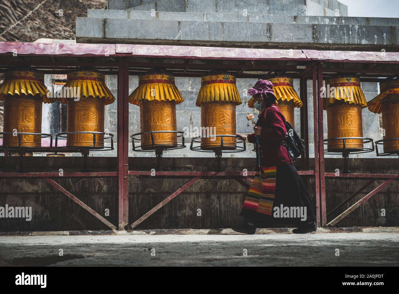 Une vieille dame tibétaine passe par roues de prière à Shigatse, au Tibet. Banque D'Images