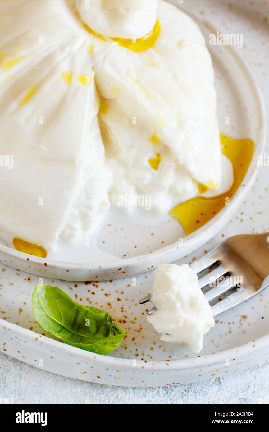 Burrata fromage italien sur une assiette avec une fourchette et basilic Banque D'Images