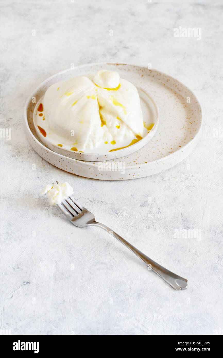 Burrata fromage italien sur une assiette avec une fourchette et l'huile d'olive Banque D'Images