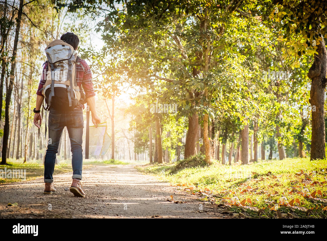 Jeune homme debout seul dans une forêt avec le coucher du soleil sur la nature historique de vie et de survie de voyage concept. Banque D'Images