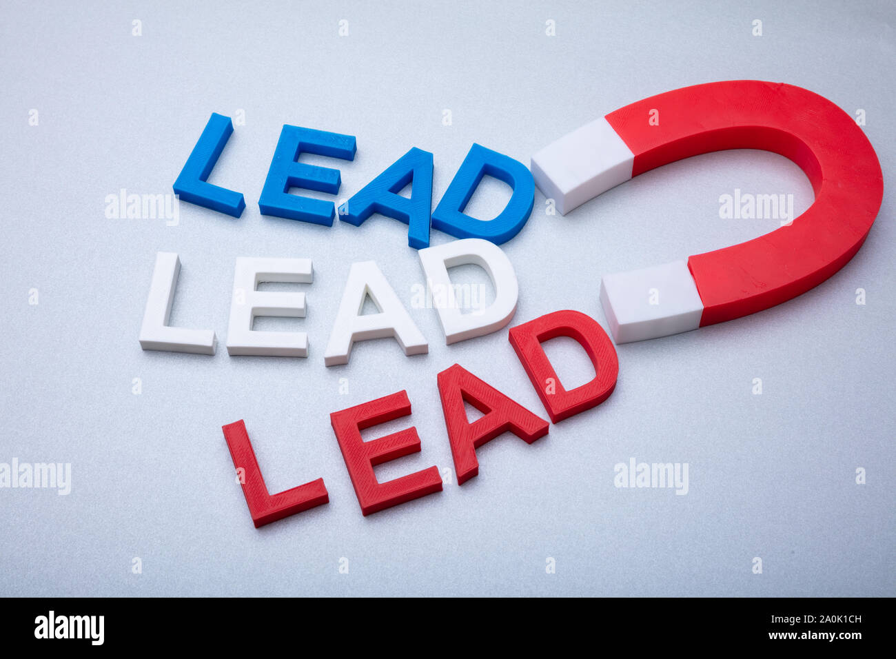 Person's Hand Holding Horseshoe aimant qui attire les câbles de couleur des lettres sur fond blanc Banque D'Images
