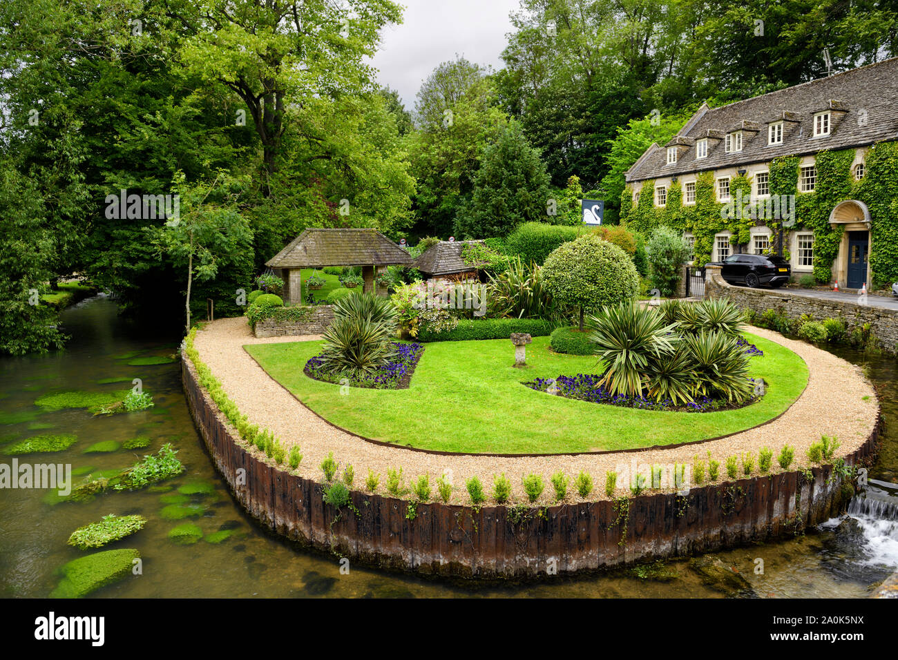 Le Swan Hotel avec jardin verdoyant parc entouré par la rivière Colne dans Bibury Angleterre Gloucester Banque D'Images