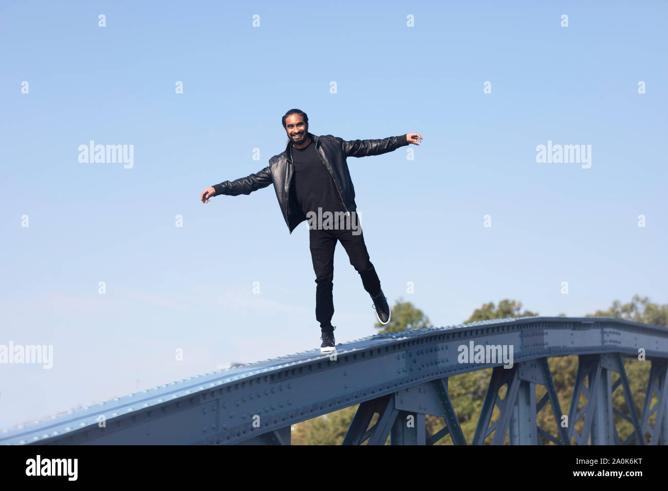 Jeune homme à la natte et la barbe en équilibre sur un pont Banque D'Images