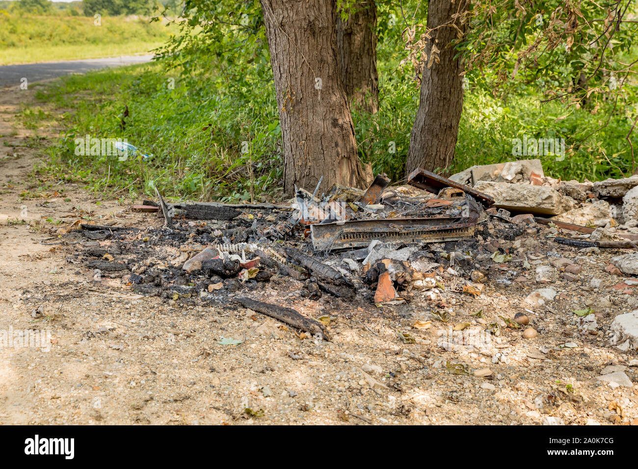 Corbeille à déchets et d'un dumping illégalement sur le côté d'une route par river et brûlés, laissant derrière une pile de débris carbonisés, métal, et le fil Banque D'Images