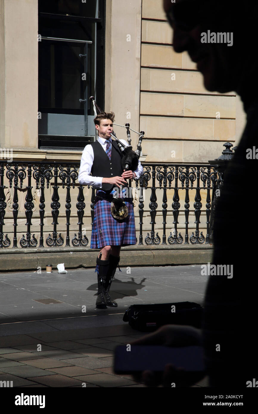 L'Écosse Glasgow Buchanan Street de cornemuse de la rue - homme marchant par avec un téléphone mobile dans la main Banque D'Images