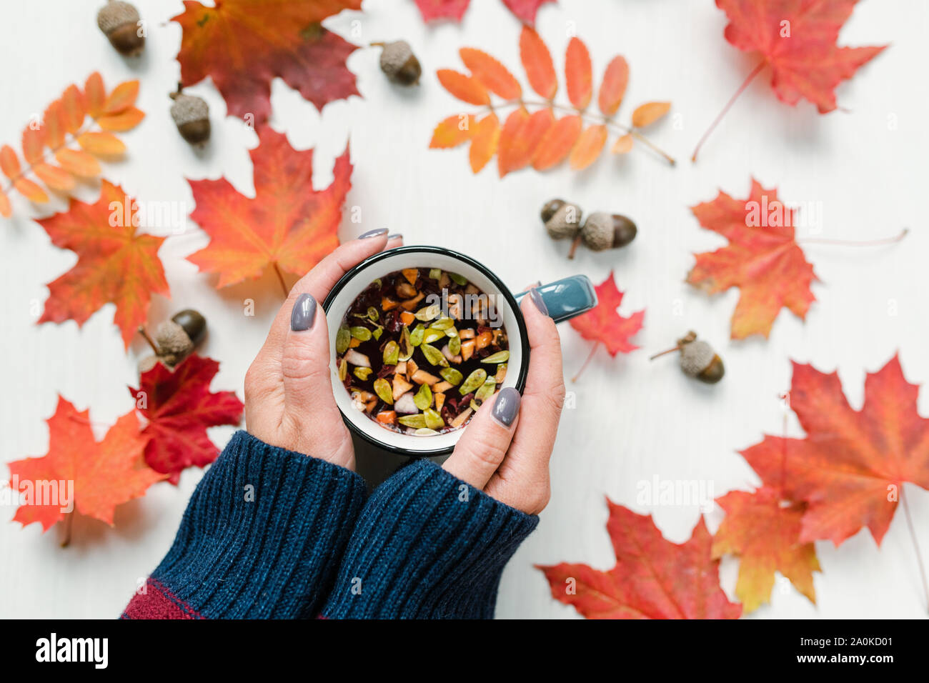 Les mains tenant un plateau sur table avec l'érable rouge et de feuilles et de glands de Rowan Banque D'Images