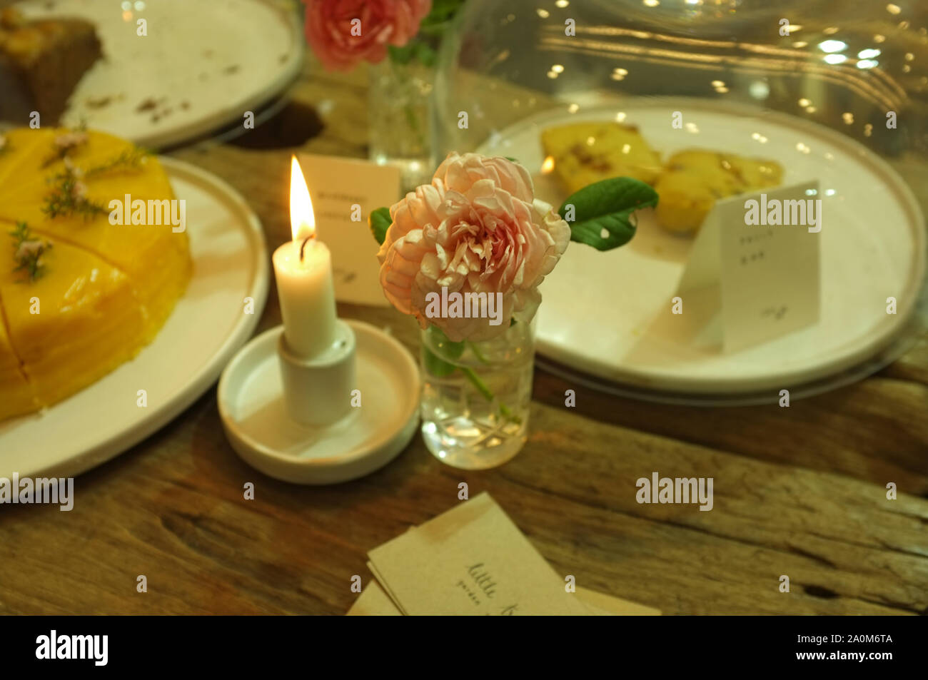 Des gâteaux, des bougies et une rose rose pour un dîner romantique Banque D'Images