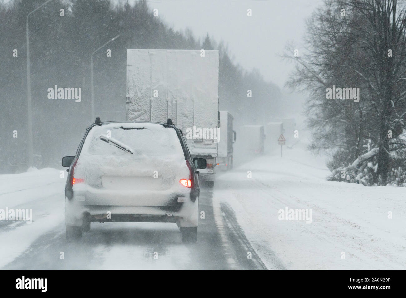 La voiture roule sur une route d'hiver dans un blizzard Banque D'Images