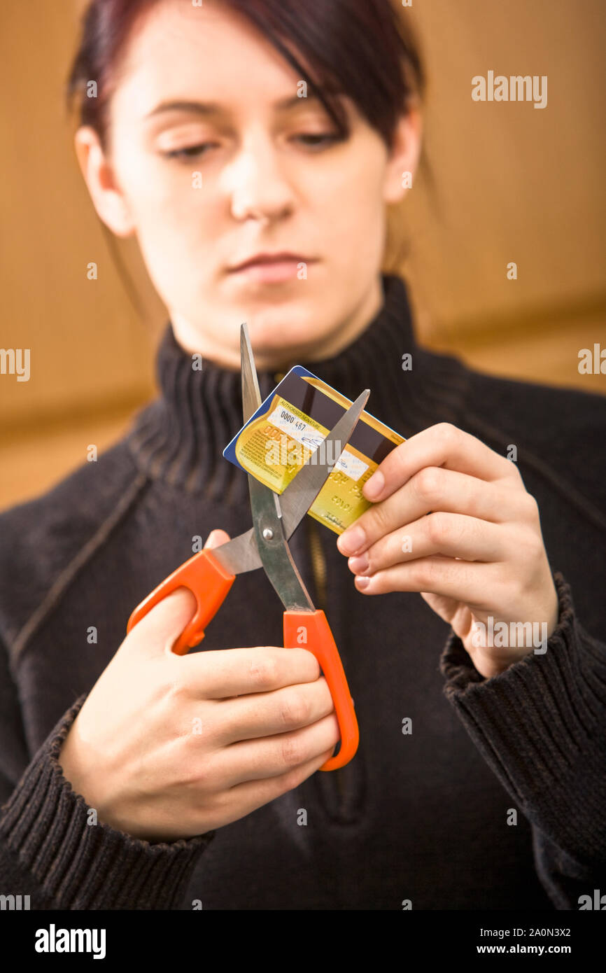 Jeune femme de couper une carte de crédit Banque D'Images