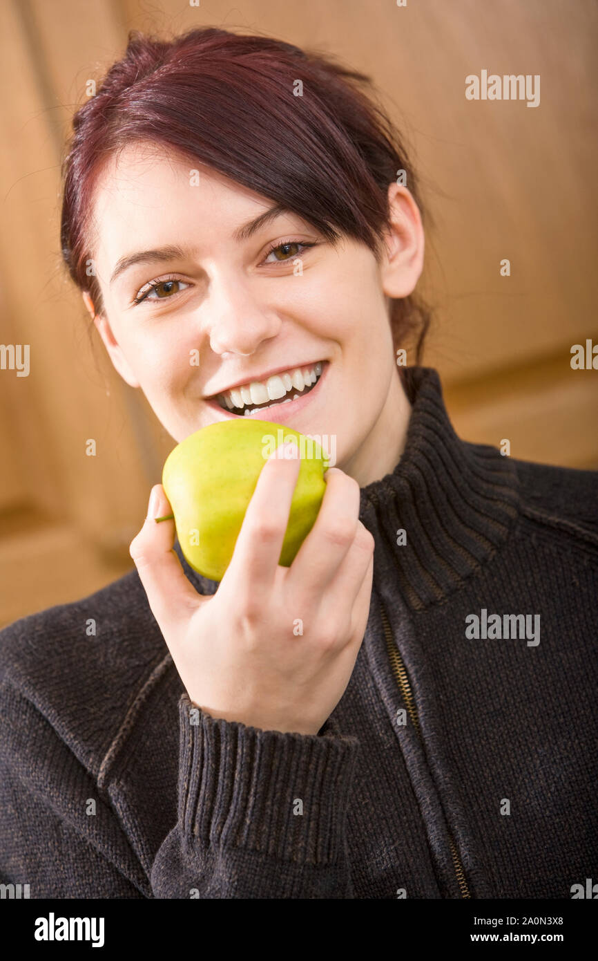 Jeune femme de manger une pomme à l'intérieur Banque D'Images