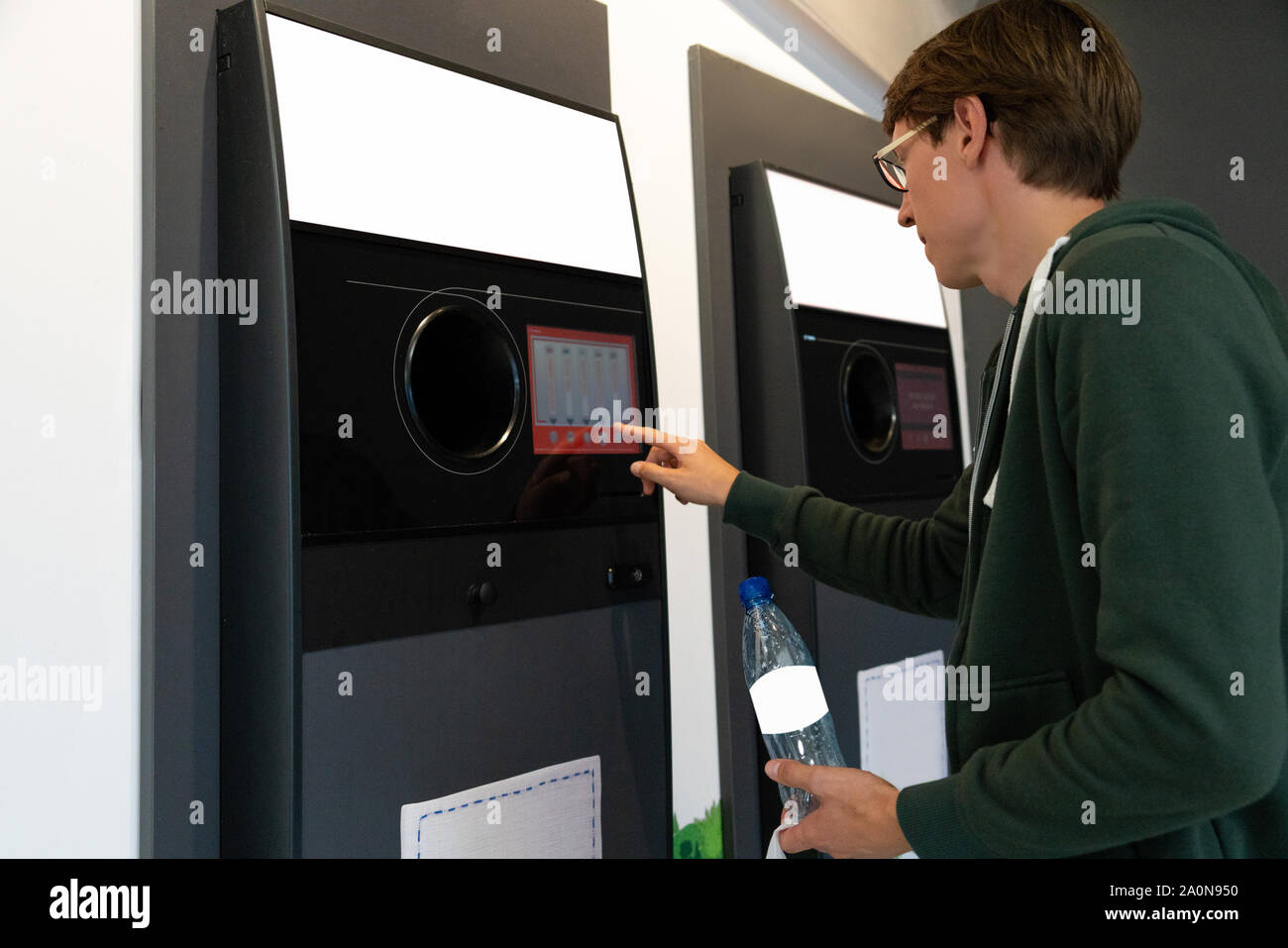 L'homme utilise une machine en libre service pour recevoir des bouteilles de plastique et les boîtes dans un magasin Banque D'Images