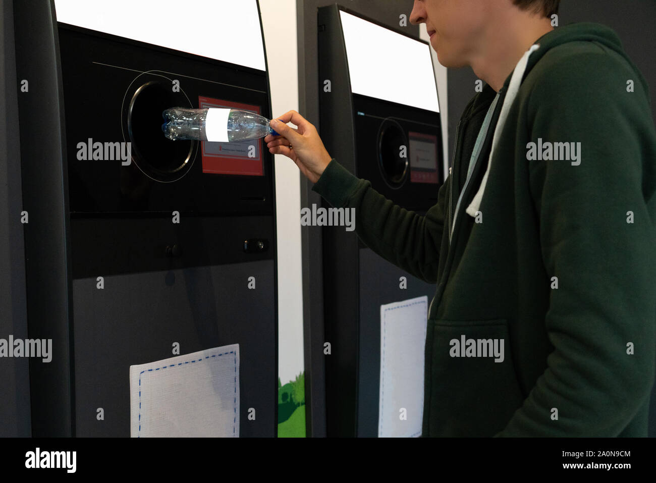 L'homme utilise une machine en libre service pour recevoir des bouteilles de plastique et les boîtes dans un magasin Banque D'Images