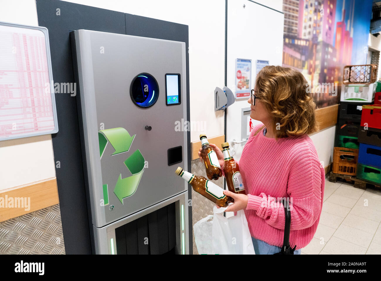 Une femme utilise un self service machine pour recevoir des bouteilles de plastique et les boîtes dans un magasin Banque D'Images