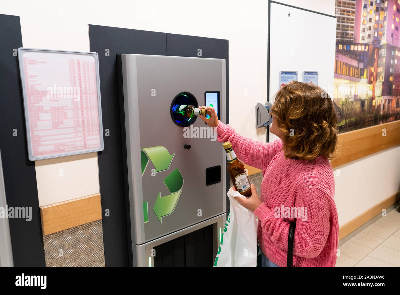Une femme utilise un self service machine pour recevoir des bouteilles de plastique et les boîtes dans un magasin Banque D'Images