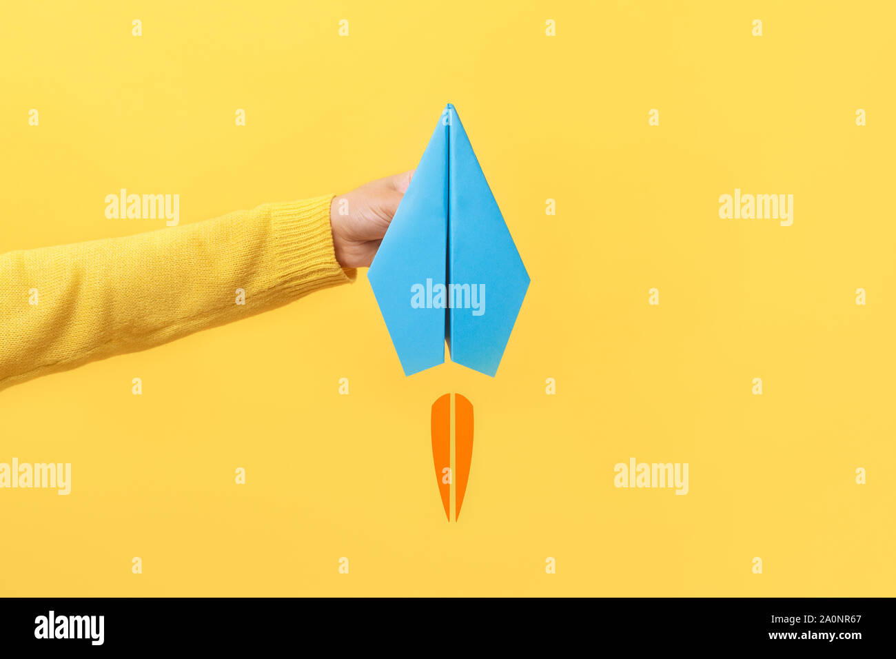 Hand holding paper plane sur fond jaune Banque D'Images
