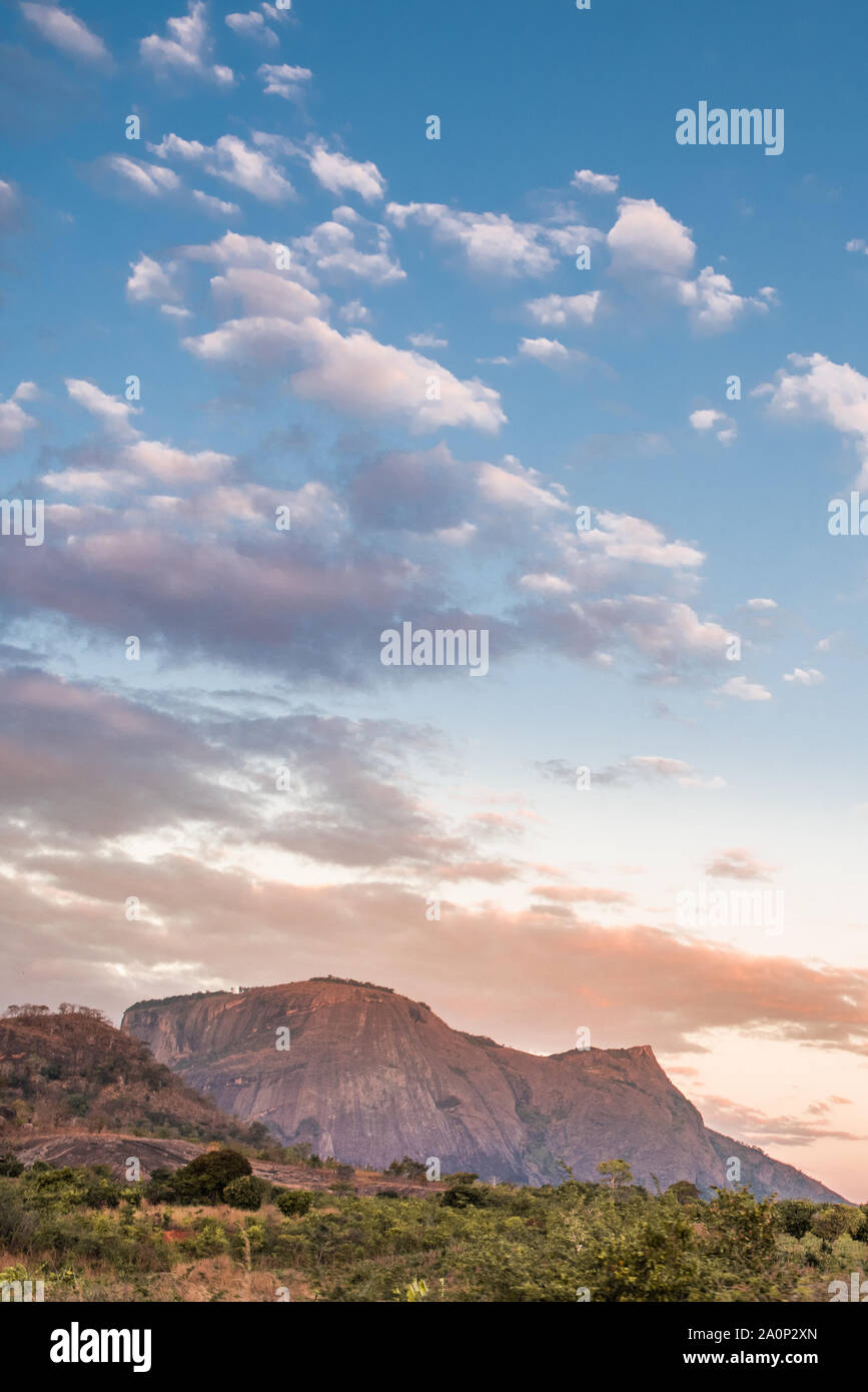 Gamme de montagne et les champs des régions rurales du Mozambique sous un ciel bleu avec des nuages roses et mauves du soleil couchant. La province de Nampula, Mozambique, Afrique du Sud Banque D'Images