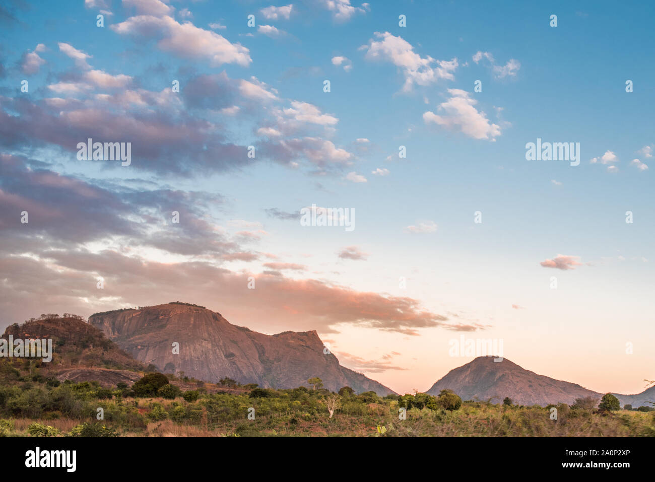 Gamme de montagne et les champs des régions rurales du Mozambique sous un ciel bleu avec des nuages roses et mauves du soleil couchant. La province de Nampula, Mozambique, Afrique du Sud Banque D'Images