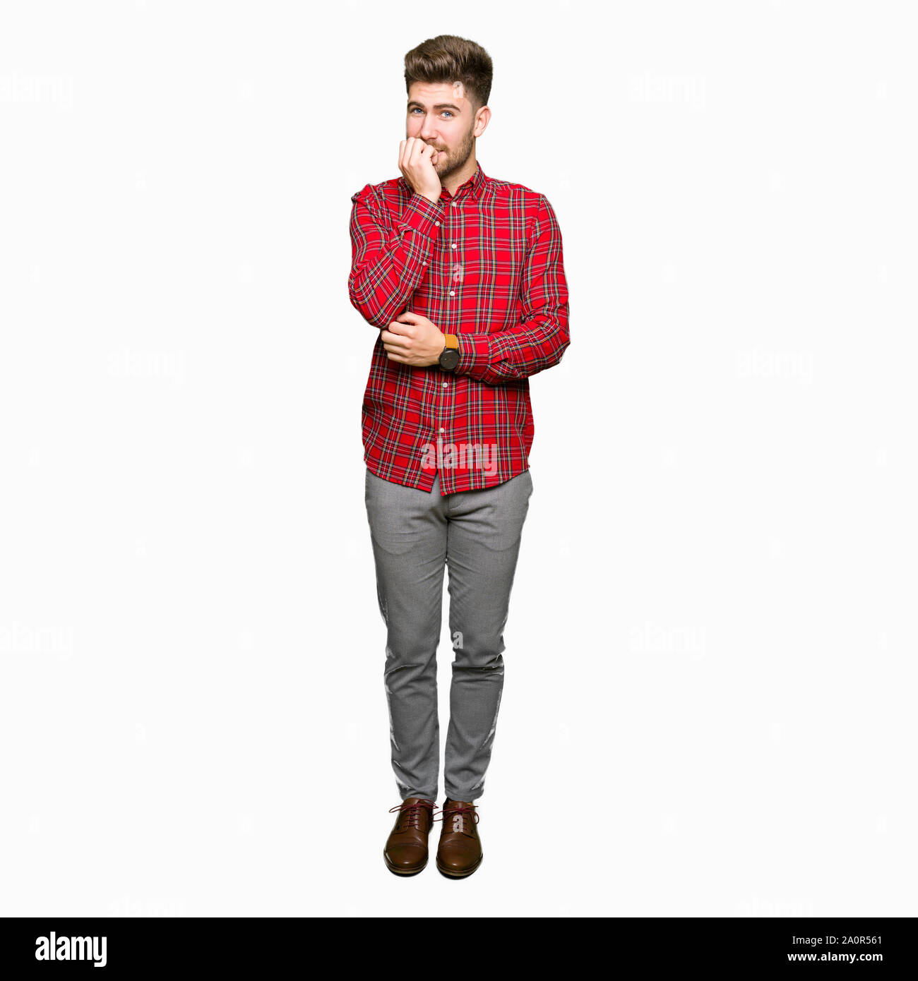 Jeune homme séduisant à souligné et nerveux avec les mains sur la bouche de mordre les ongles. Problème d'anxiété. Banque D'Images