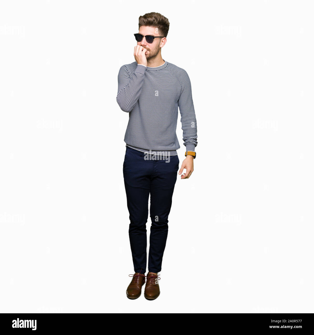 Beau jeune homme portant des lunettes de soleil à souligné et nerveux avec les mains sur la bouche de mordre les ongles. Problème d'anxiété. Banque D'Images