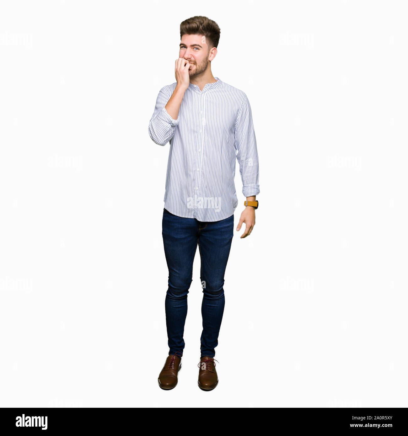 Jeune homme séduisant à souligné et nerveux avec les mains sur la bouche de mordre les ongles. Problème d'anxiété. Banque D'Images