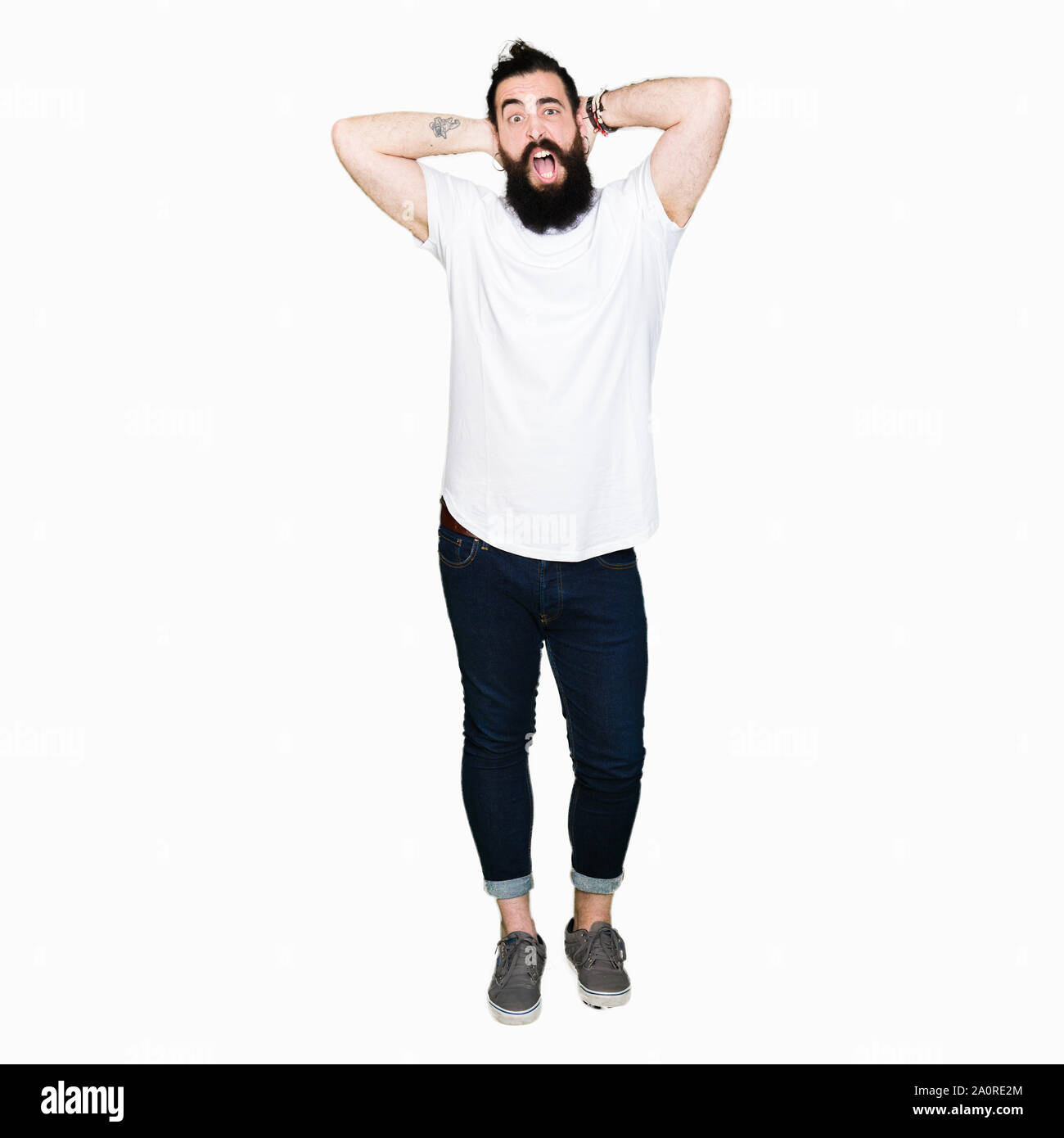 Jeune homme hipster avec de longs cheveux et barbe porter Casual t-shirt blanc et fou de peur, peur et surprise de choc avec ouvrir m Banque D'Images