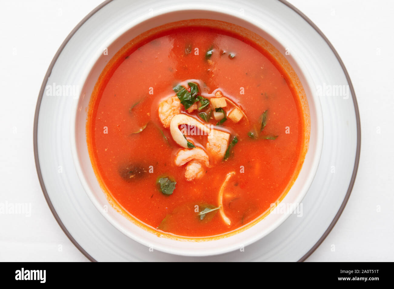 Soupe de tomate avec des poissons et crustacés en profonde assiette de porcelaine en plongée des Banque D'Images