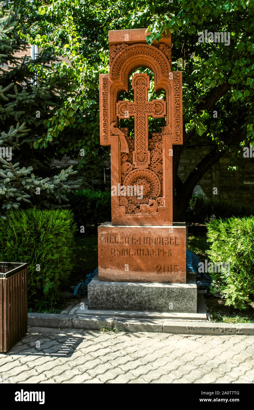 Khatchkar tuf rouge avec une croix dans un passage à motifs sur un cercle avec les chiffres d'un oiseau et d'un chevreuil,dans le parc sur le territoire de l'Église 'Zoravor' Banque D'Images