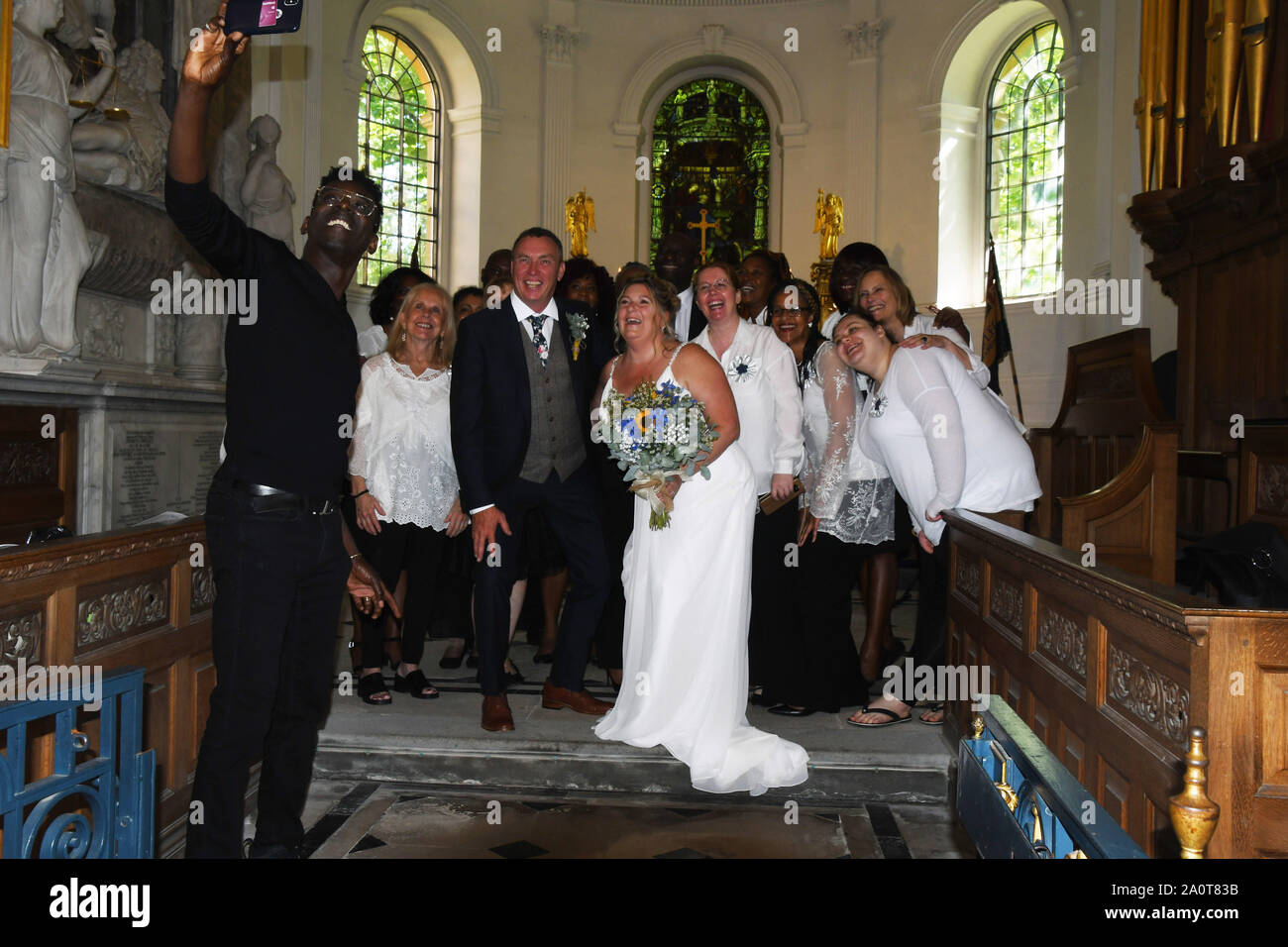 Les mariés aiment avoir leur photo prise avec le Chœur Gospel qui avait chanté à leur mariage dans une belle église de campagne de l'Ouest. Banque D'Images Les mariés aiment avoir leur photo prise avec le Chœur Gospel qui avait chanté à leur mariage dans une belle église de campagne de l'Ouest. Banque D'Images