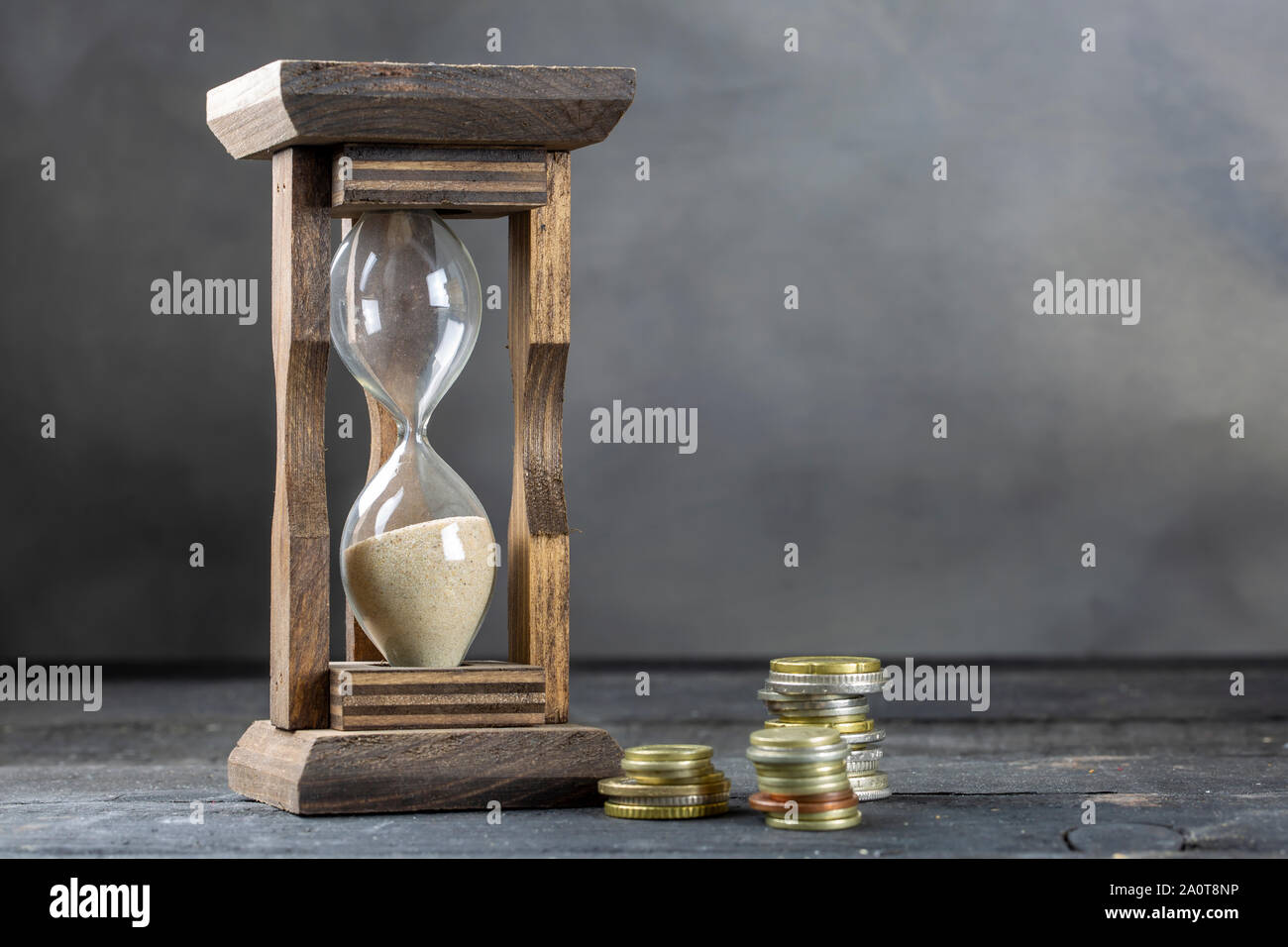 Le temps est argent concept, coin et hourglass Banque D'Images