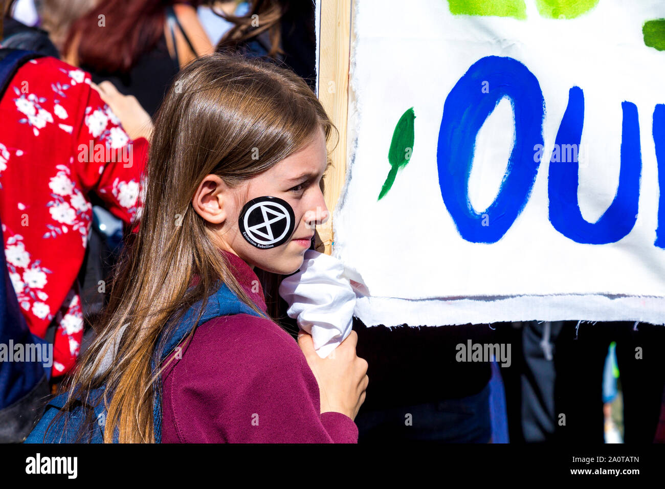 20 septembre 2019, Londres, Royaume-Uni - Jeune fille avec une rébellion Extinction autocollant sur son visage tenant une bannière dans le climat mondial grève dans Westminster Banque D'Images