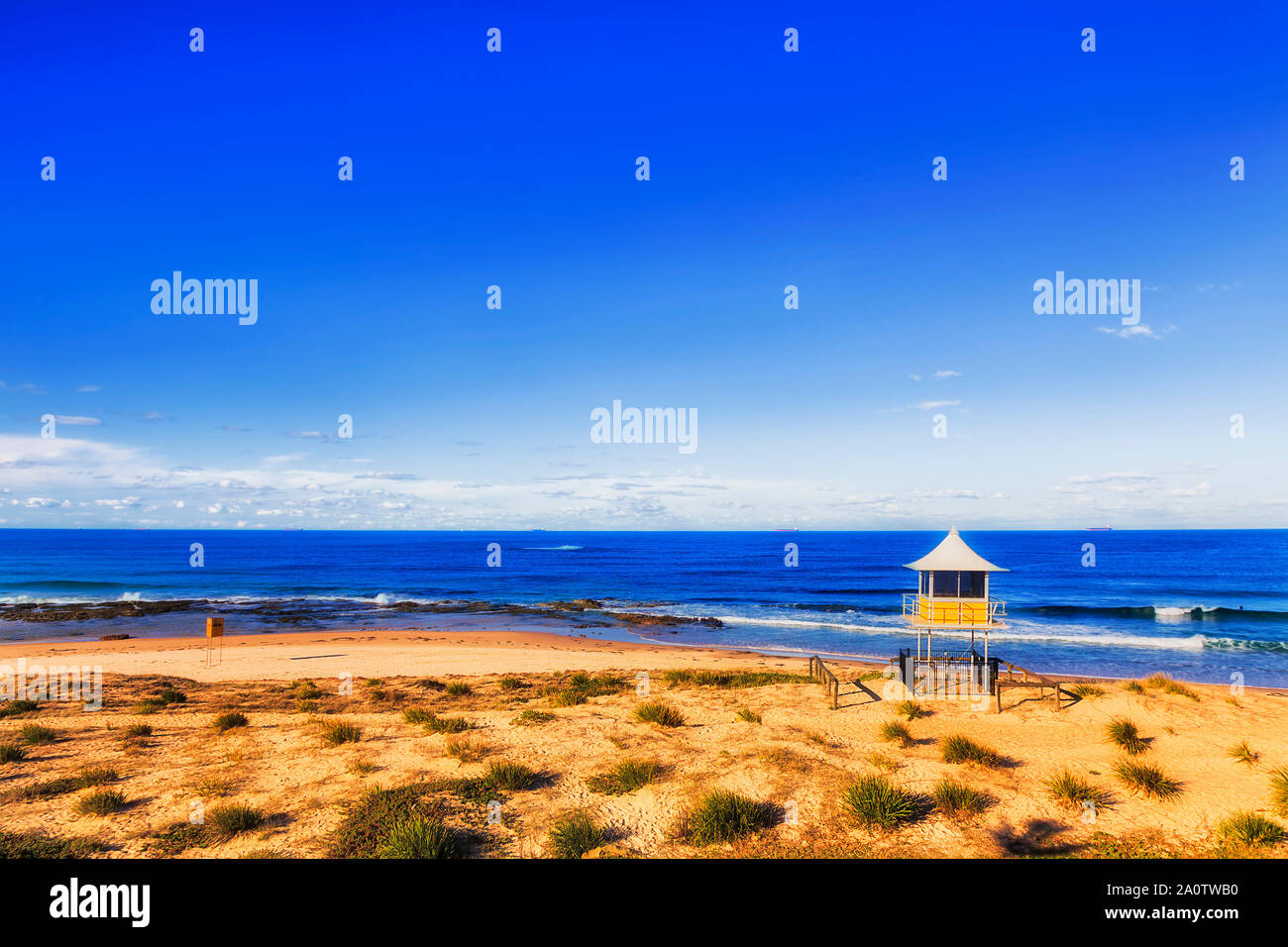 Plage de sable à distance sur la côte du Pacifique de l'Australie avec maître nageur et d'observation life savers watch hut surplombant les amateurs de plage à vagues d'ouvrir Banque D'Images