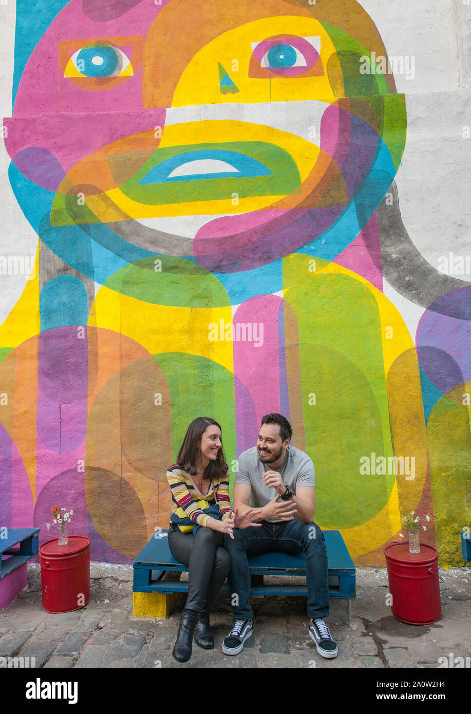 Un couple sur un banc de fortune sur une rue dans le quartier Vila Madalena de São Paulo, Brésil. Banque D'Images