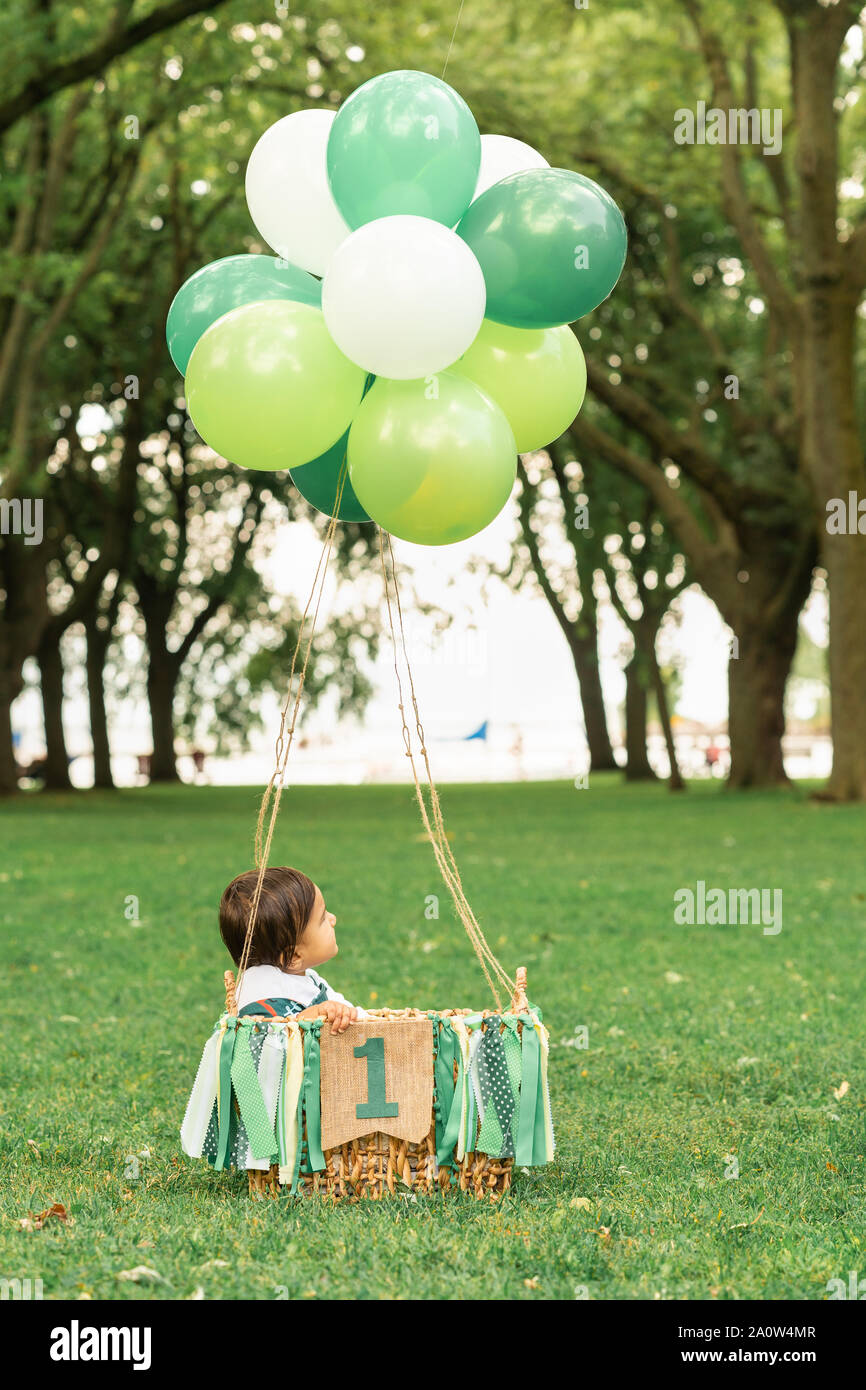 Mignon Bebe Assis Dans Un Panier Tisse Avec Des Ballons Et Un Ruban Vert Banniere Qui Se Lit Un Vol En Montgolfiere Lunatique Dans Une Belle Foret C Photo Stock Alamy