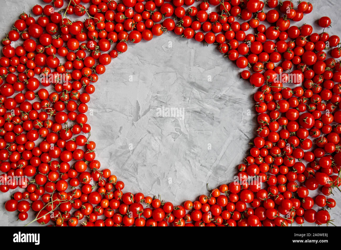 Cadre rond de tomates cerise sur un fond gris. Mise à plat. Copier l'espace. Banque D'Images