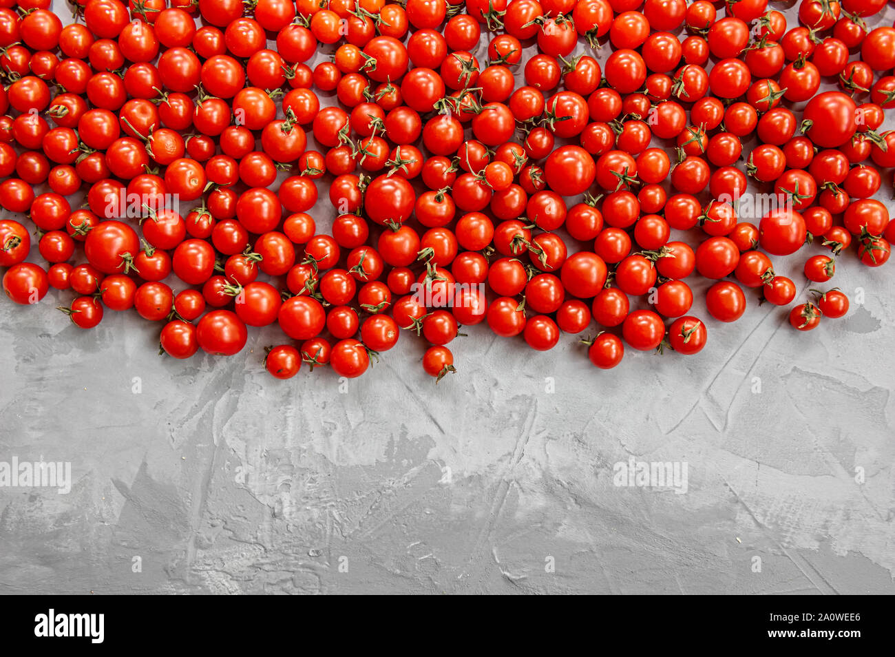 Tomate cerise sur un fond gris. Mise à plat, vue du dessus. Banque D'Images