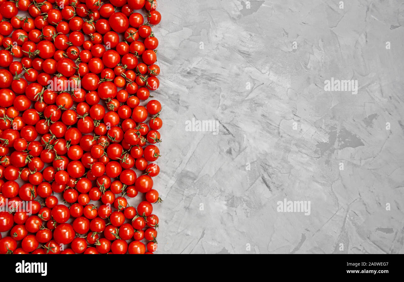 Tomate cerise sur un fond gris. Mise à plat, vue du dessus. Banque D'Images
