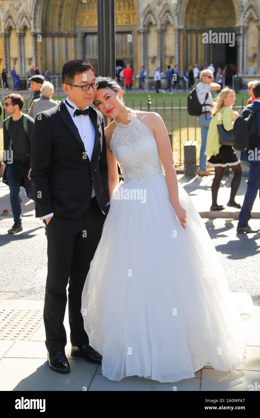Un couple chinois se faire prendre en photos en face de l'abbaye de Westminster, London, UK Banque D'Images