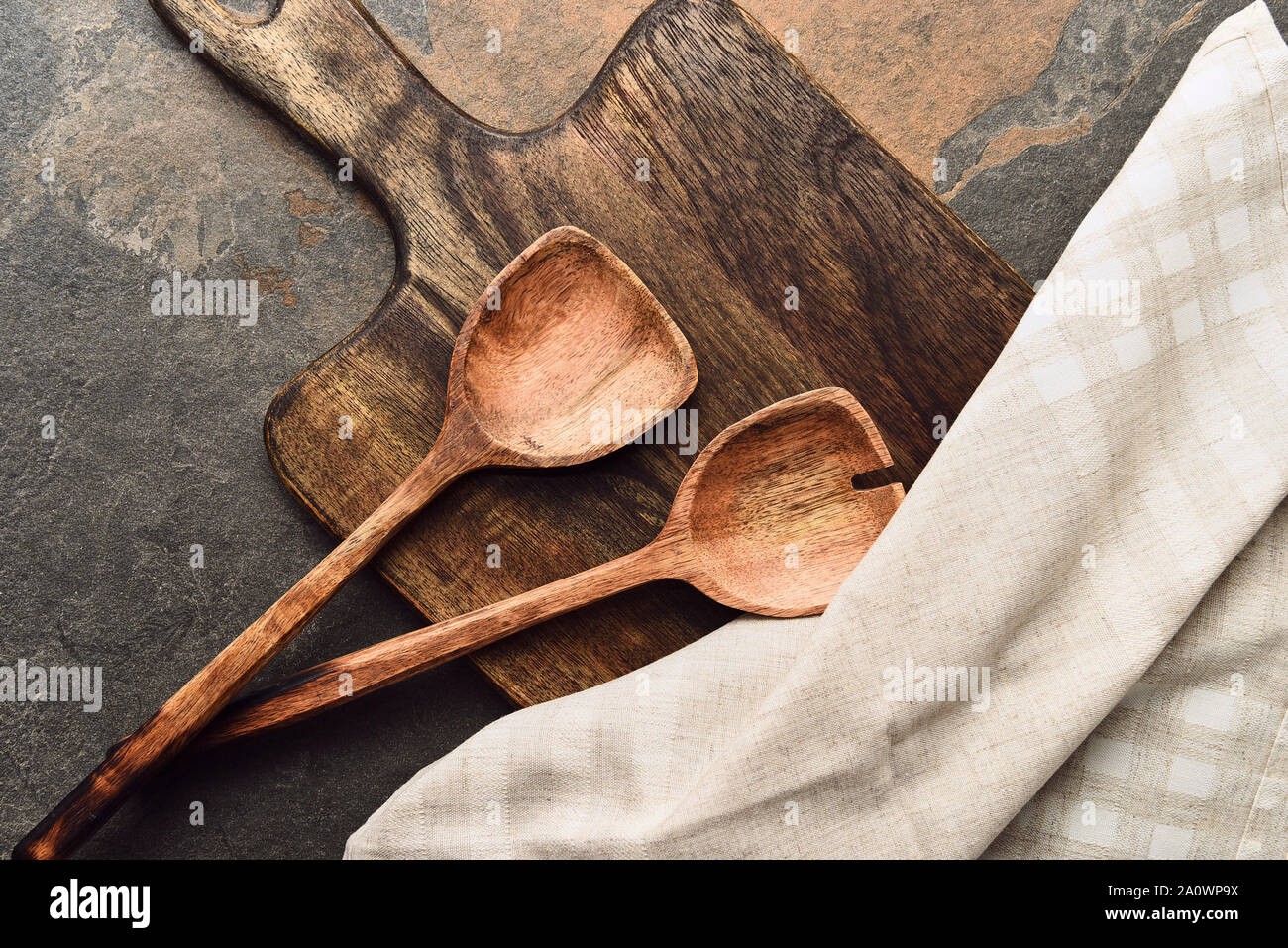 Vue de dessus de planche à découper en bois avec des spatules et serviette sur fond patiné Banque D'Images