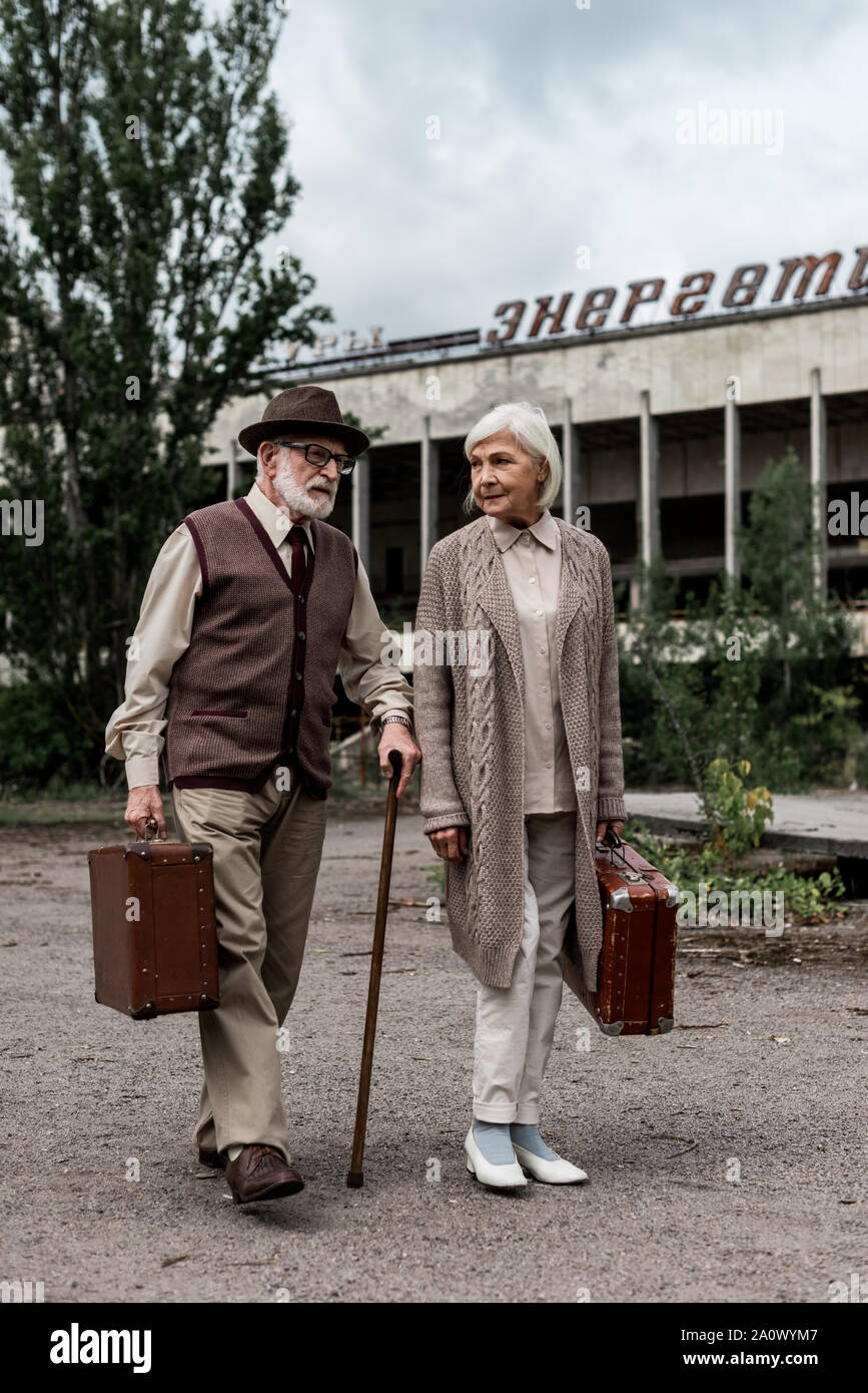 PRIPYAT, UKRAINE - le 15 août 2019 : couple de retraités avec des valises près du bâtiment avec lettrage énergique à Tchernobyl Banque D'Images