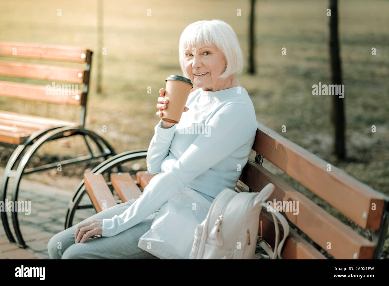 Bien-toiletté senior woman drinking coffee pour aller dans le parc Banque D'Images