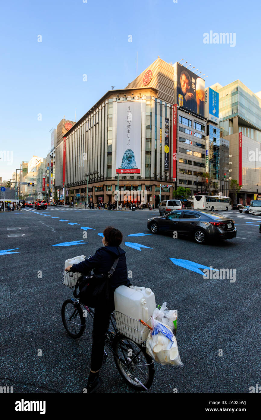 Ginza de Tokyo, l'échange avec 4 femme sur le trafic passé location en premier plan et le magasin Mitsukoshi en face. Ciel bleu. L'espace négatif. Banque D'Images