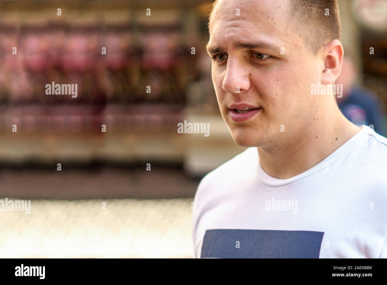 Young man in Casual T-shirt marche dans une rue urbaine avec un regard pensif Banque D'Images